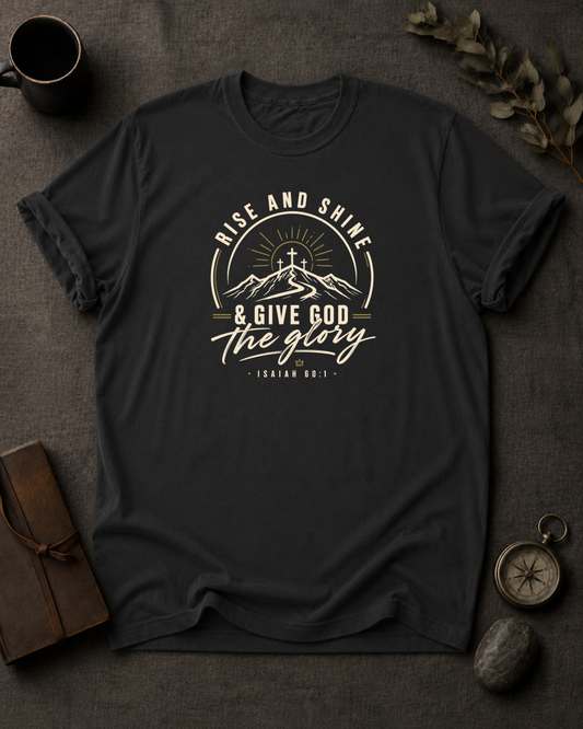 black Comfort Colors t-shirt with "Rise and Shine & Give God the Glory" Isaiah 60:1 mountain sunrise cross design in Bay colorway, styled with coffee mug, compass, and leather journal