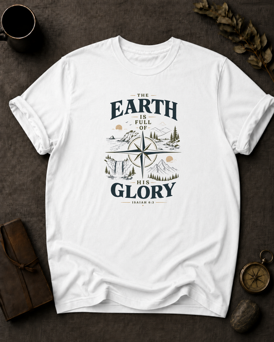 white Comfort Colors t-shirt with "The Earth Is Full of His Glory" Isaiah 6:3 compass rose landscape design in Bay colorway, styled with coffee mug, compass, and leather journal